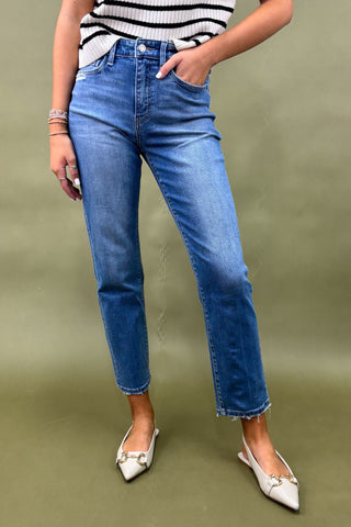 Person wearing blue jeans and a striped top on a green background