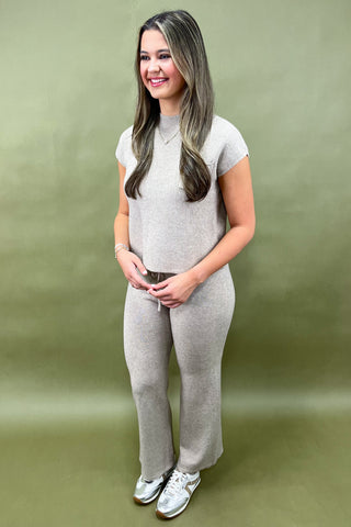Woman wearing a gray outfit against a green background