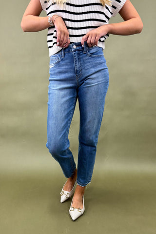 Person wearing a striped shirt and blue jeans on a green background