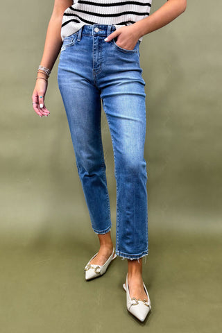 Person wearing blue jeans and white shoes on a green background