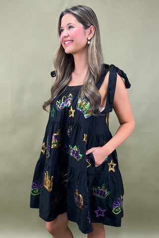 Woman wearing a black dress with colorful patterns on a green background