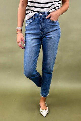 Person wearing blue jeans and a striped top on a green background