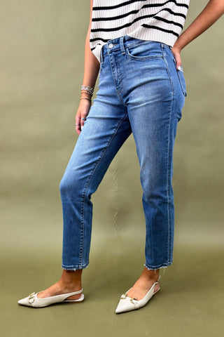 Person wearing blue jeans and a striped top on a green background