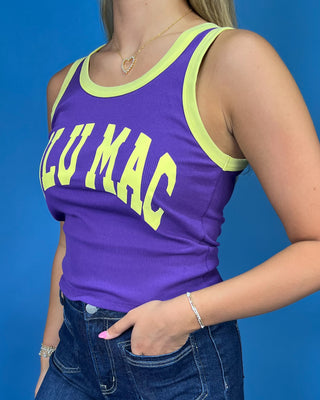 A woman modeling a purple sleeveless tank top with yellow trim and 'LULU MAC' printed in yellow across the front, paired with dark blue jeans