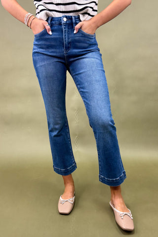 Person wearing blue jeans and a striped top on a green background