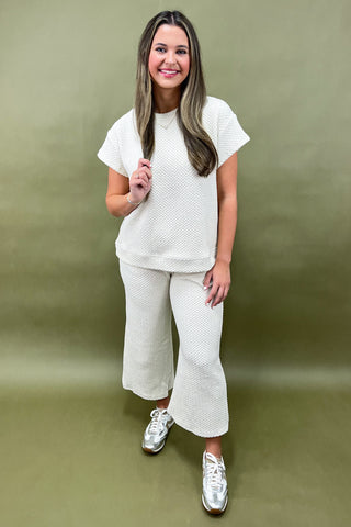 Woman wearing a white outfit with a plain background