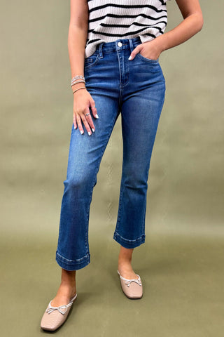 Person wearing blue jeans and a striped top on a green background