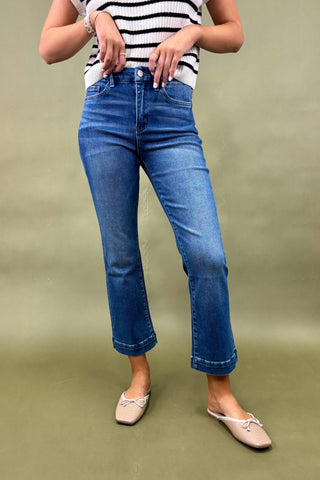 Person wearing blue jeans and a striped shirt on a green background