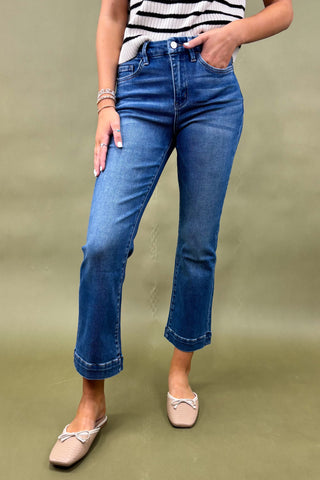 Person wearing blue jeans and a striped top on a green background