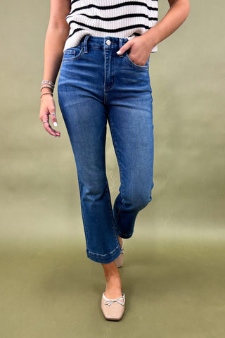 Person wearing blue jeans and a striped shirt on a green background
