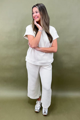 Woman wearing a white textured outfit against a green background