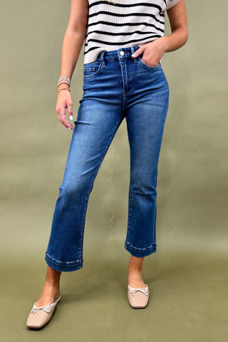 Person wearing blue jeans and a striped shirt on a green background