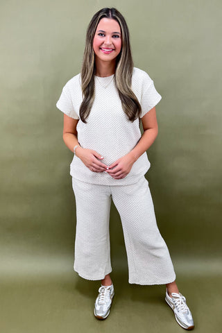 Woman wearing a white textured outfit against a green background