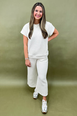 Woman wearing a white textured outfit against a green background