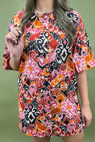 Woman wearing a colorful patterned dress against a green background