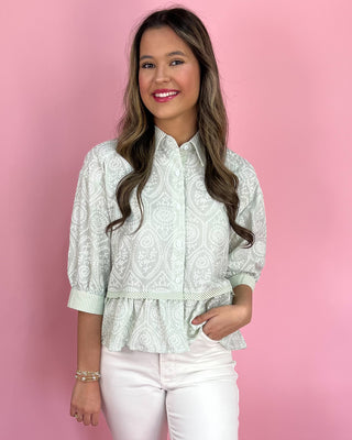Woman wearing a white patterned blouse against a pink background