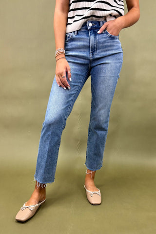 Person wearing blue jeans and a striped top on a green background