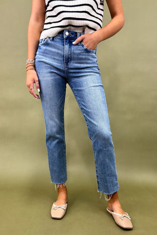 Person wearing blue jeans and a striped top on a green background