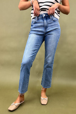 Person wearing blue jeans and a striped shirt on a green background