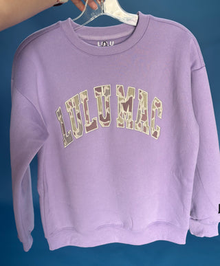 Camo Lilac Crewneck Sweatshirt with a camo appliqué, fleece-lined interior, relaxed fit, and soft cotton-blend comfort.