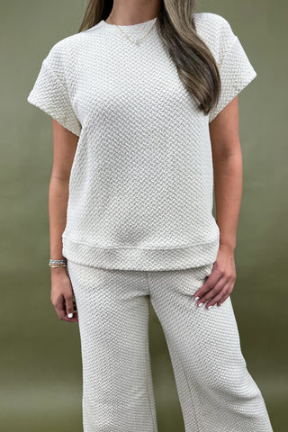 Person wearing a textured white outfit against a plain background