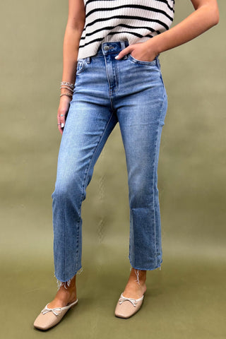 Person wearing blue jeans and a striped top on a green background
