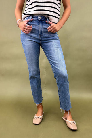 Person wearing blue jeans and a striped top on a green background