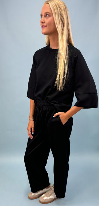 Person wearing a black outfit on a light blue background