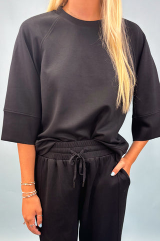 Person wearing a black outfit with a plain background
