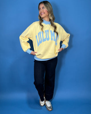 Yellow Lulu Mac sweatshirt with light blue lettering, mock neck, cuffs, and hem for a sporty color-block look.