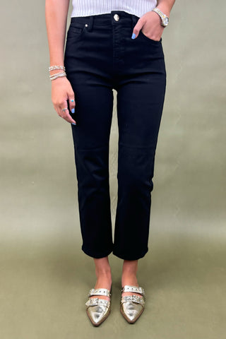 Person wearing black jeans and silver shoes on a plain background