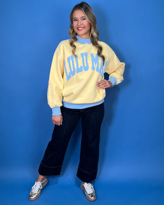 Yellow Lulu Mac sweatshirt with light blue lettering, mock neck, cuffs, and hem for a sporty color-block look.