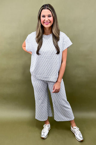 Woman wearing a white patterned outfit against a green background
