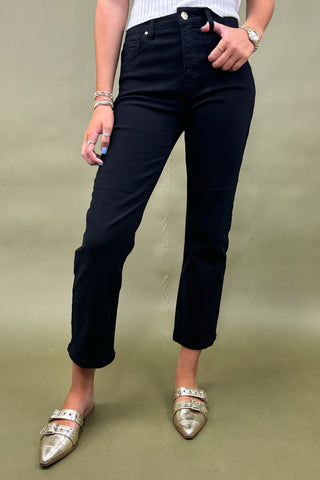 Person wearing black pants and gold shoes on a green background