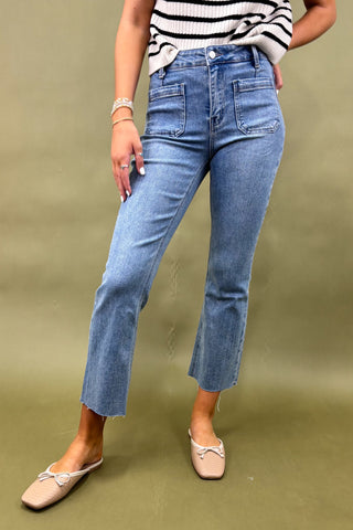Person wearing blue jeans and a striped shirt on a green background
