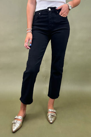 Person wearing black pants and gold shoes on a green background