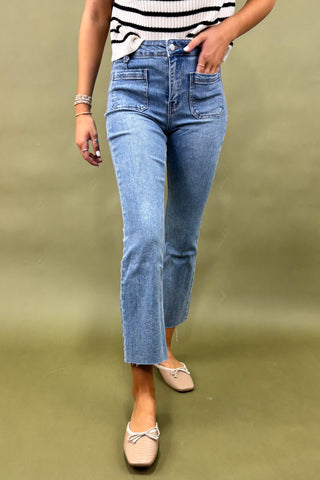 Person wearing blue jeans and a striped shirt on a green background