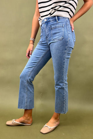 Person wearing blue jeans and a striped top on a green background