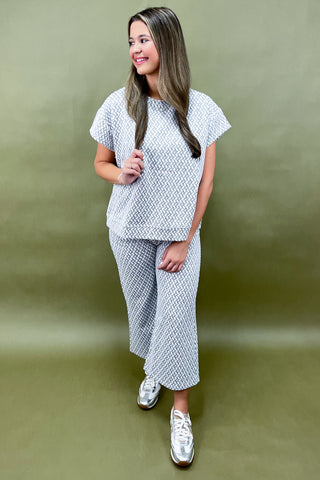Woman wearing a patterned outfit against a green background