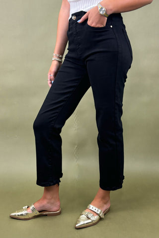Person wearing black pants and gold shoes on a green background