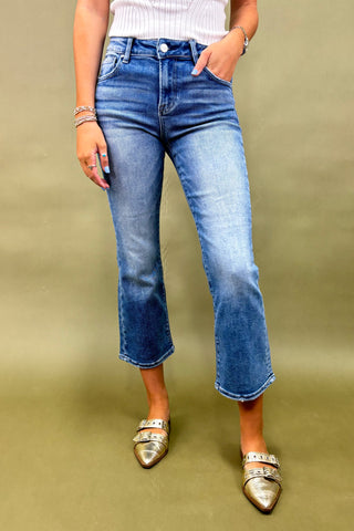 Person wearing blue jeans and metallic shoes on a beige background