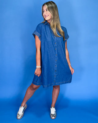 Woman wearing a blue denim dress against a blue background