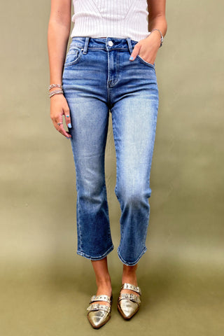 Person wearing blue jeans and gold shoes on a plain background