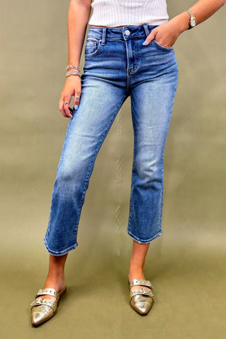 Person wearing blue jeans and gold flats on a green background