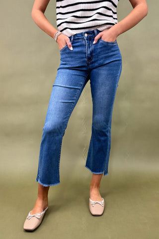 Person wearing blue jeans and a striped shirt on a green background
