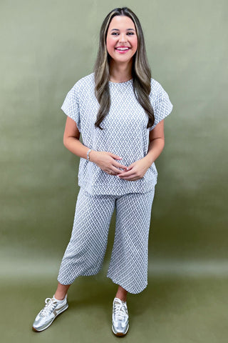 Woman wearing a matching top and pants set against a green background
