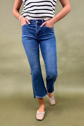 Person wearing blue jeans and a striped shirt on a green background