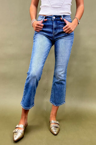 Person wearing blue jeans and silver shoes on a plain background