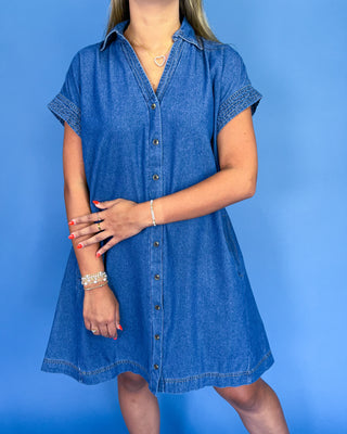 Woman wearing a blue denim dress against a blue background