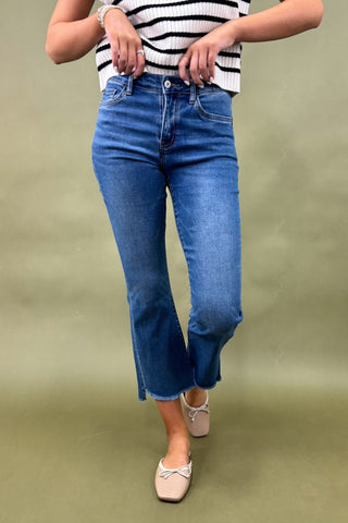 Person wearing blue jeans and a striped shirt on a green background